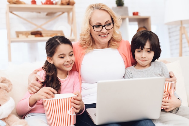 Grootmoeder knuffelen kinderen kijken naar film op laptop