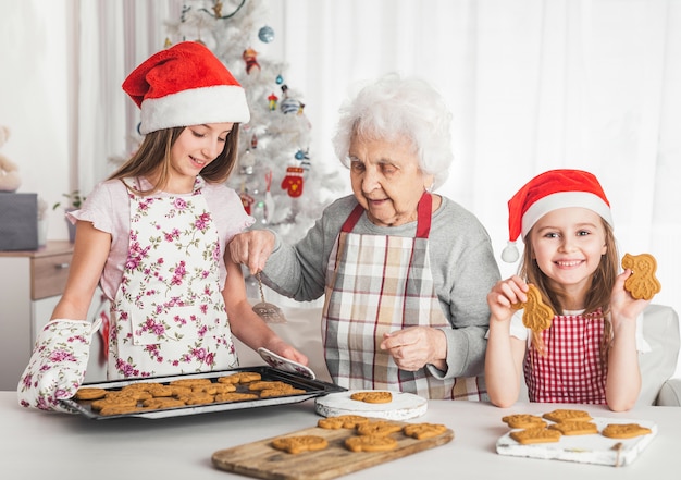 Grootmoeder met kleindochters die koekjes bakken