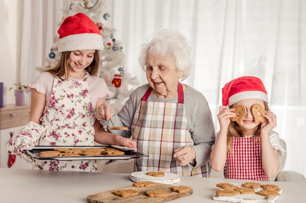 Grootmoeder met kleindochters die koekjes bakken