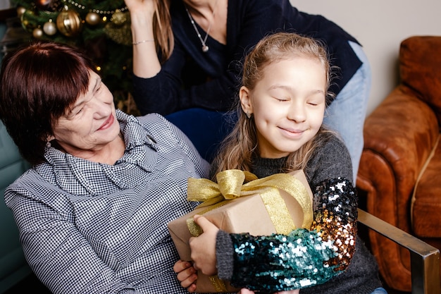 Grootmoeder omhelst en geeft haar kleindochter een kerstcadeau. Gelukkig gezin concept.