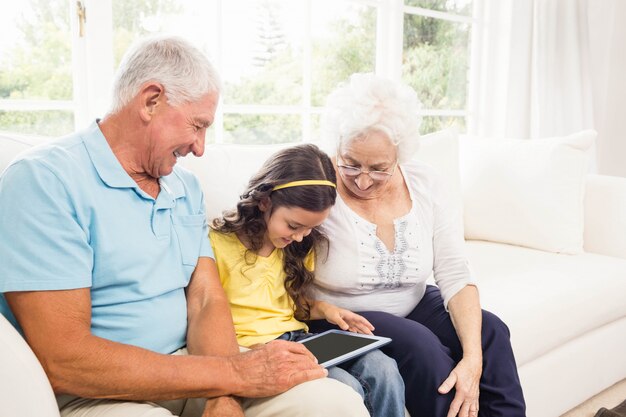 Grootouders die tablet met hun kleindochter thuis gebruiken