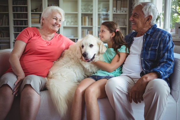 Grootouders en kleindochterzitting op bank met huisdierenhond