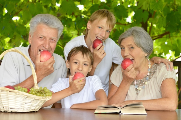 Grootouders en kleinzonen met appels in de zomer aan tafel