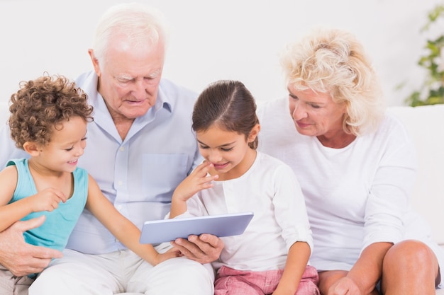 Grootouders met kinderen die een tabletpc gebruiken