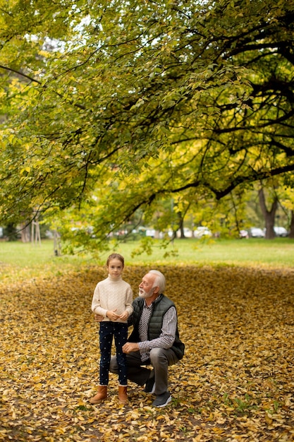 Grootvader brengt op herfstdag tijd door met zijn kleindochter in het park