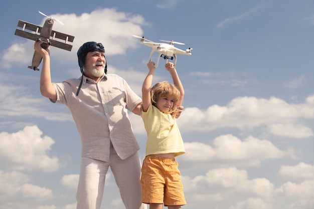 Grootvader en kleinzoon houden vliegtuig en drone quadcopter kind jongen piloot vlieger met vliegtuig dromen o