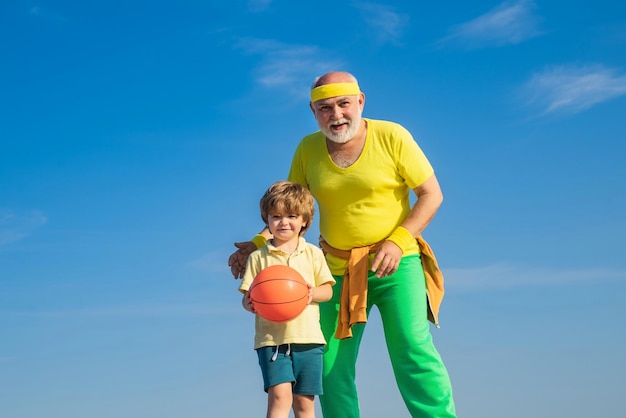 Grootvader en kleinzoon met basketbalbal en yogamat in handen Gezondheidszorg vrolijke levensstijl Gezond leven en sportconcept