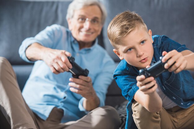 Grootvader en kleinzoon spelen videogame met joysticks