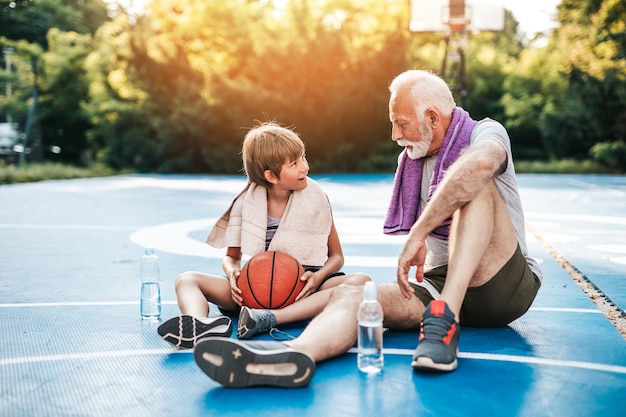 Grootvader en zijn kleinzoon genieten samen op het basketbalveld.