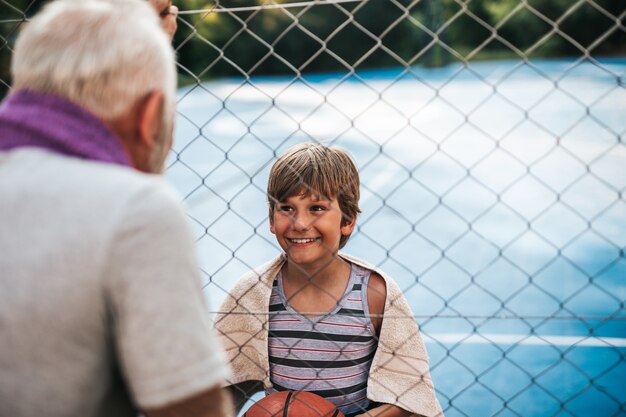 Grootvader en zijn kleinzoon genieten samen op het basketbalveld.