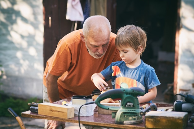 Grootvader en zijn kleinzoon hebben plezier in de buitenworkshop