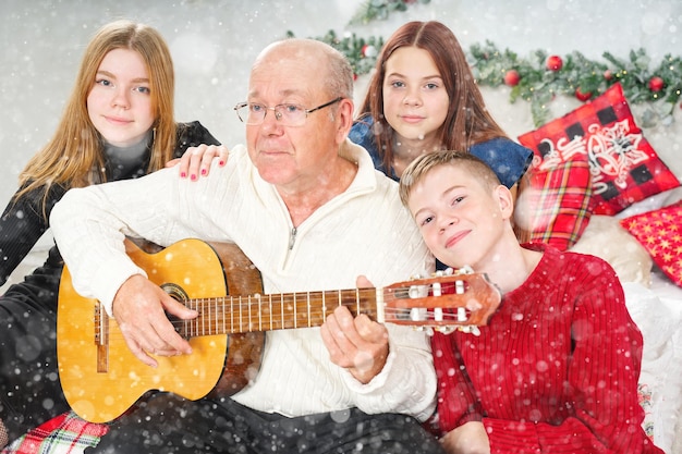 Grootvader gitaar spelen tijdens kerstmis voor kleinkinderen Gelukkige man jaren '60 gitaar spelen kerstliederen