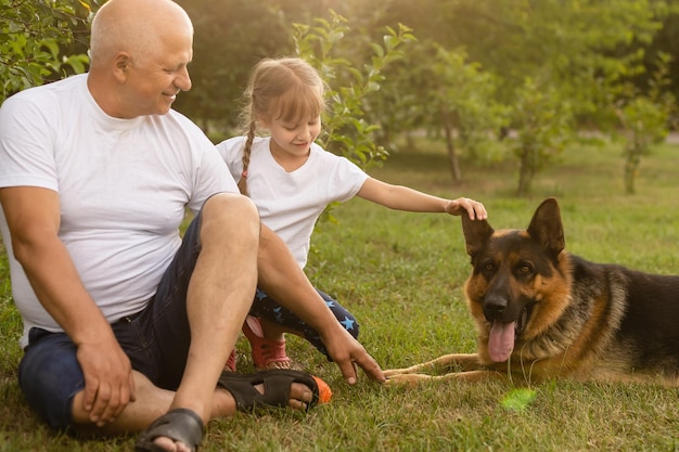 Grootvader met kleindochter en een hond in de tuin