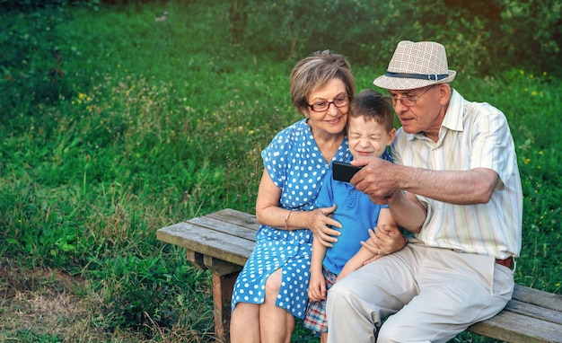 Grootvader neemt selfie met oma en kleinzoon zittend op een bankje