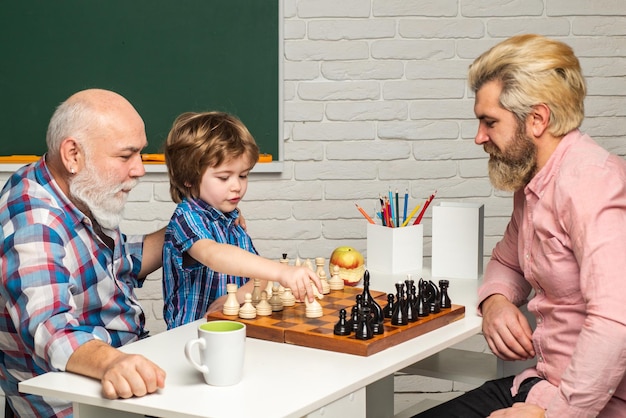 Grootvader vader en zoon die schaak opa spelen die achterkleinzoon lesgeven op schoolklas man generatie co