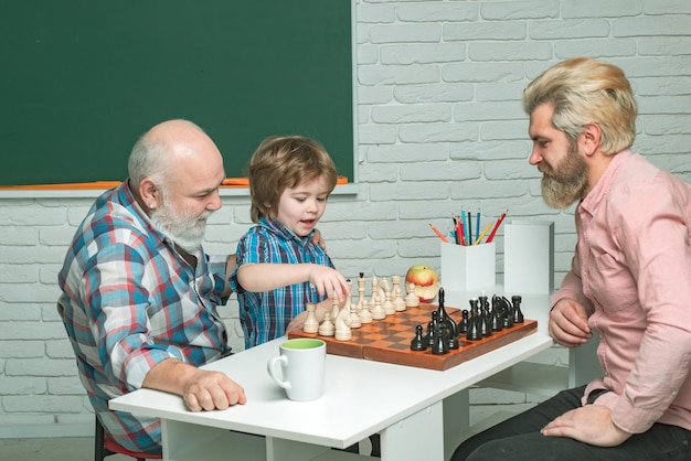 Grootvader, vader en zoon spelen schaakmannen in verschillende leeftijden, klaar om een gelukkig gezin in de klas te studeren