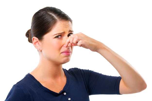 Gross Studio shot of a young woman holding her nose isolated on white