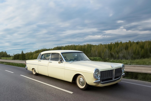 Foto grote beige oude klassieke auto op de weg