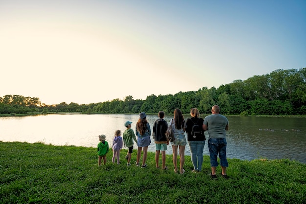 Grote en grote familie tegen meer in zonsopgang Zes kinderen Ouders en kinderen