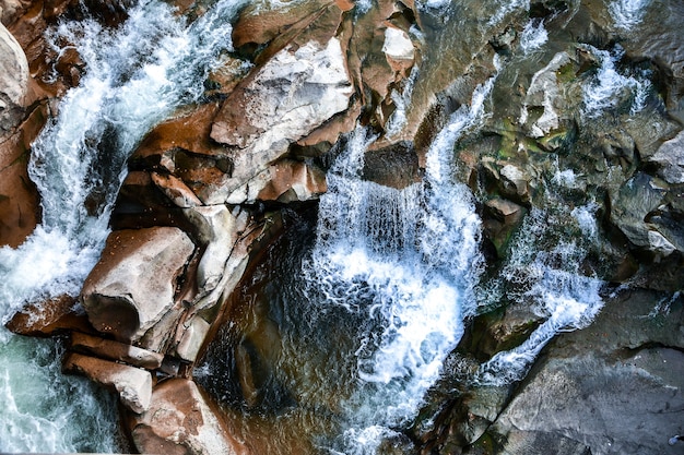 Grote en kleine stenen in de buurt van de beek. De bergen. De textuur van de steen. Achtergrond. Water valt op de rotsen. Schoonheid in de natuur