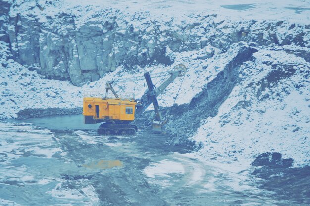 Grote enorme gele graafmachine in een granietgroeve in de winter.