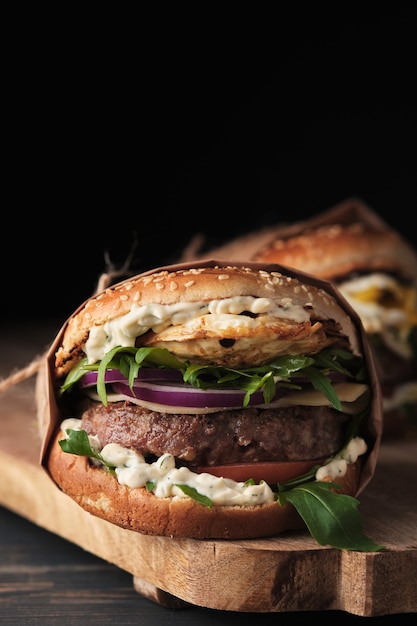 Grote gegrilde hamburger met groenten op een houten bord