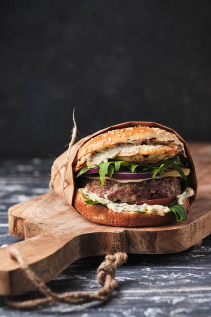 Grote gegrilde hamburger met groenten op een houten bord