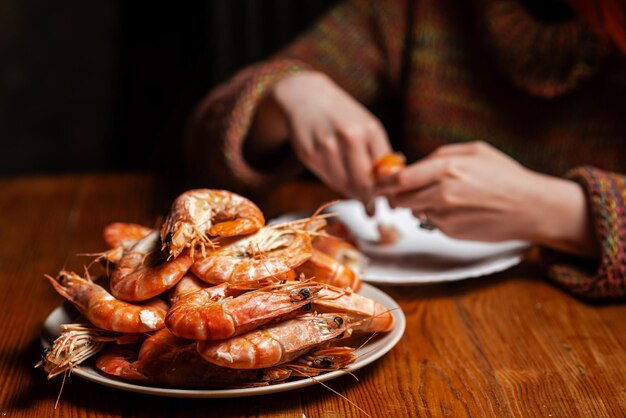 Grote gekookte reuzengarnalen op tafel Een onherkenbaar man zit garnalen te eten aan tafel