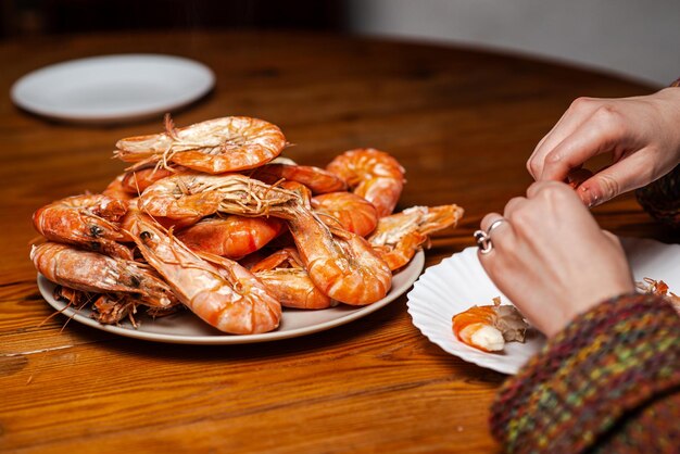 Grote gekookte reuzengarnalen op tafel Een onherkenbaar man zit garnalen te eten aan tafel