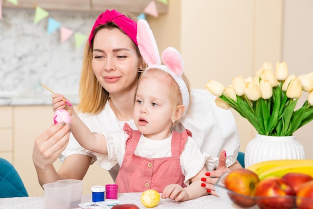 Grote gelukkige familie die zich voorbereidt op Pasen Schattig meisje met moeder die eieren schildert Thuisactiviteit Concept van eenheid en liefde Moeder en dochter