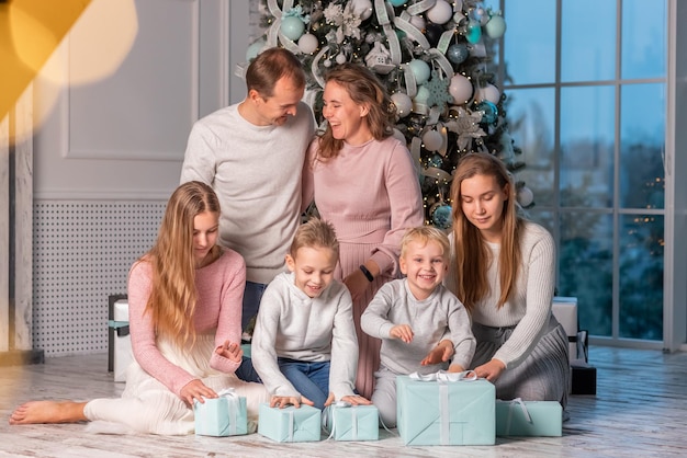Grote gelukkige familie met veel kinderen die plezier hebben en cadeautjes openen onder de kerstboom. Kerst familieavond, kerststemming concept