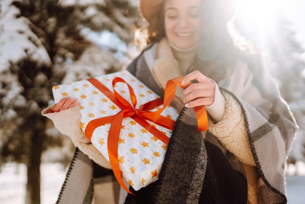 Grote geschenkdoos met rood lint in de handen van de vrouw Mode jonge vrouw met een kerstcadeau