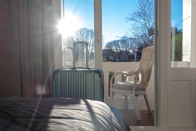 Grote groene koffer blijft in de kamer in hotel bij raam of balkon met zonlicht