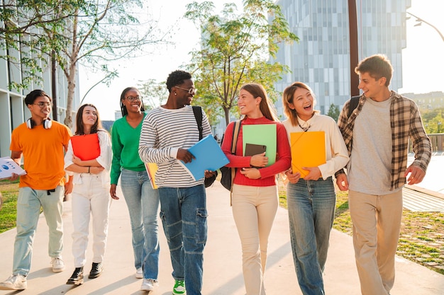 Grote groep internationale klasgenoten lopen en praten samen op de universiteitscampus gelukkig