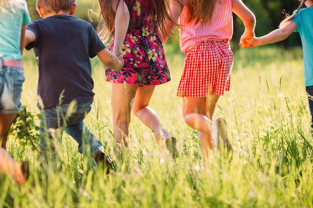 Grote groep kinderen, vrienden jongens en meisjes die in het park op zonnige zomerdag in vrijetijdskleding lopen.