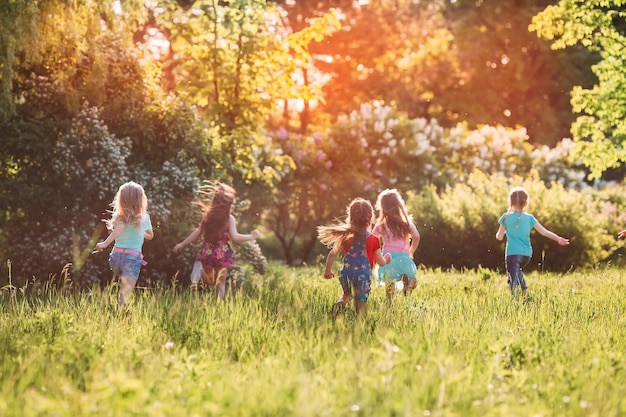 Grote groep kinderen, vrienden jongens en meisjes rennen in het park op zonnige zomerdag in vrijetijdskleding.