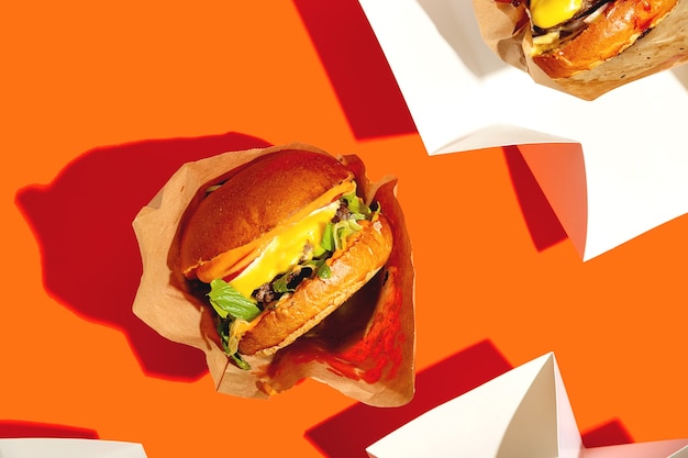 Grote hamburger met kaas in een pakket op een fel oranje achtergrond fastfood levering