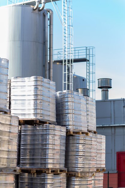 Grote hoeveelheid aluminium biervaten gestapeld op elkaar met euro-paletten en omhuld met vinylfolie