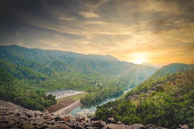 Foto grote hydro-elektriciteitsdam elektriciteitscentrale met berg en zonsondergang op de achtergrond voor hernieuwbare energieconcept