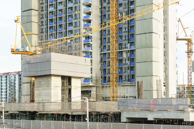 Grote industriële torenkranen met onafgewerkte hoog opgeheven gebouwen en blauwe hemel