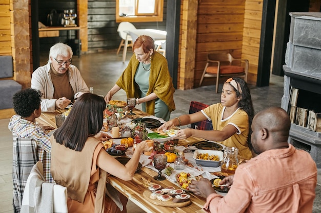 Grote interraciale familie die aan een feestelijke tafel zit?