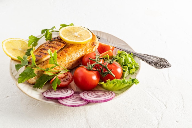 Grote keramische plaat met gegrilde kipfilet en verse groenten op een witte achtergrond heerlijk eten ruimte voor tekstmenu