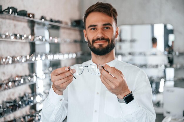 Grote keuze Stijlvolle man met baard die een bril kiest in de optiekwinkel