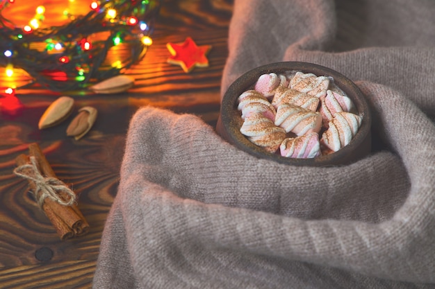Grote kop warme chocolademelk met marshmallow, kaneel en verpleegster en warme deken op een oude vintage houten en kerstlicht. Gezellig kerst- of herfstarrangement.