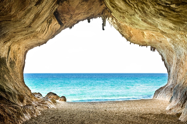 Grote lege grot met toegang tot blauwe zee en geel zandstrand. europa, italië, sardinië