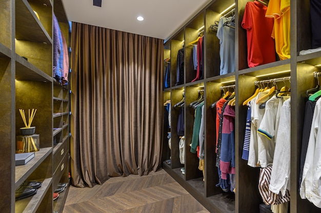 Grote luxe herengarderobe met verschillende kledingschoenen en accessoires, vooraanzicht