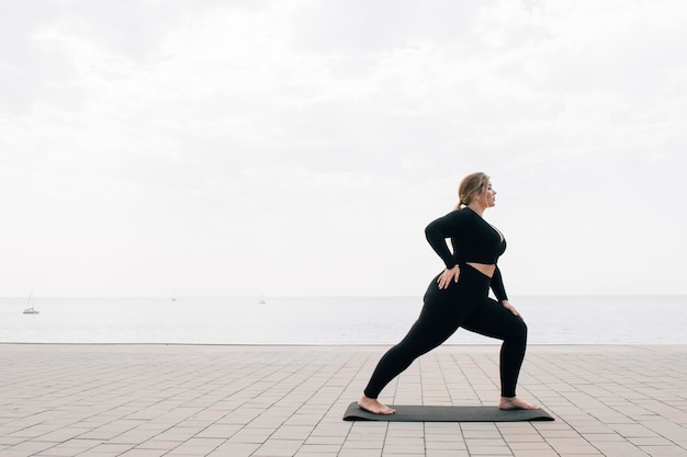 Grote maten meid die yoga beoefent voor de oceaan