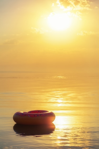 Grote opblaasbare donut op het water bij zonsondergang