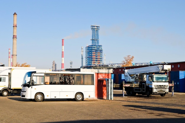 Grote open sapvrachtwagen vrachtwagens trekkers vrachtwagens bussen kranen op een industriële fabriek transportwinkel bouwmachines op de achtergrond van pijpen