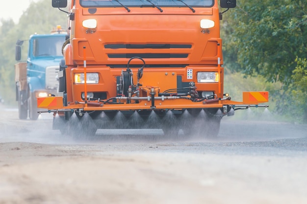 Grote oranje machine ruimt het asfalt op met waterstromen